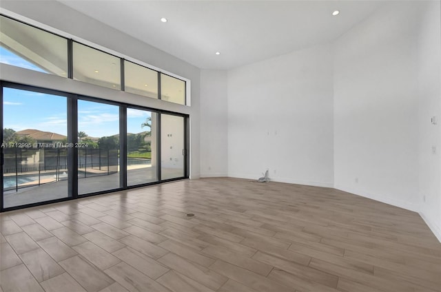 empty room featuring a high ceiling and light hardwood / wood-style flooring