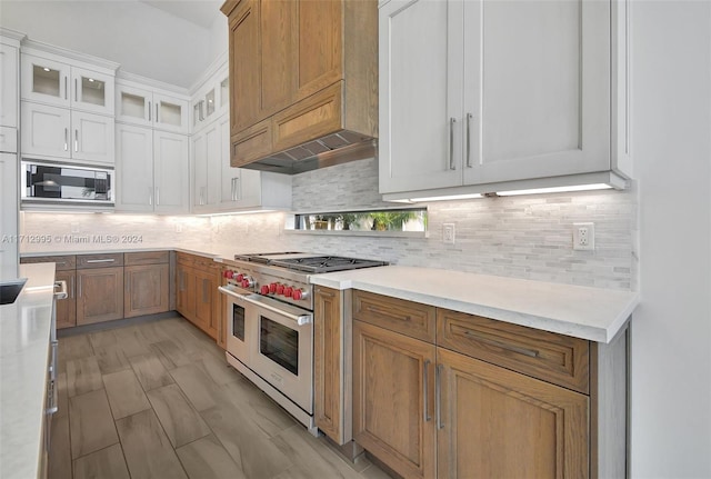 kitchen with premium range hood, appliances with stainless steel finishes, decorative backsplash, white cabinets, and light wood-type flooring