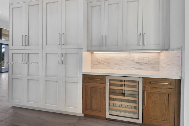 bar with tasteful backsplash, white cabinetry, and beverage cooler