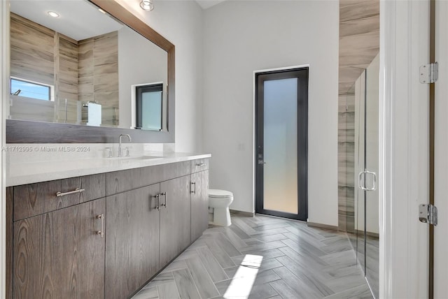 bathroom with parquet flooring, vanity, toilet, and walk in shower