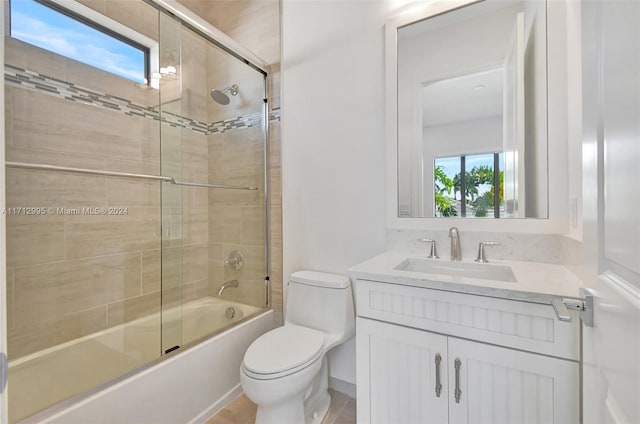 full bathroom with vanity, toilet, a wealth of natural light, and bath / shower combo with glass door