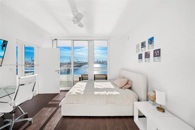 bedroom with ceiling fan, dark hardwood / wood-style flooring, and a water view