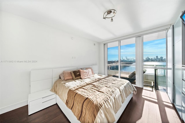 bedroom with floor to ceiling windows, a water view, and hardwood / wood-style flooring