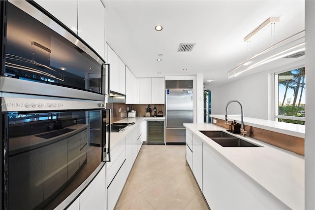 kitchen with black electric cooktop, sink, white cabinets, built in refrigerator, and wine cooler