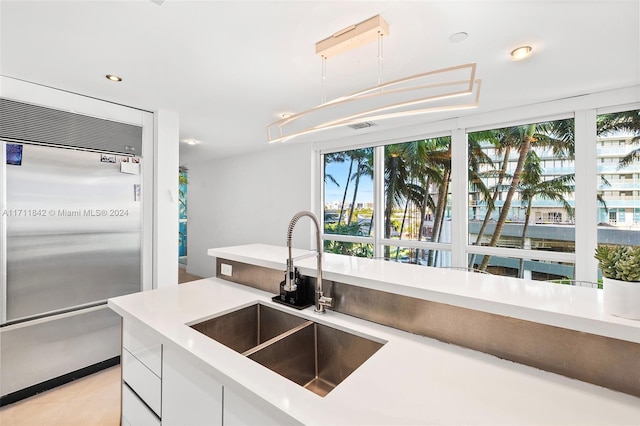 kitchen featuring white cabinets, light tile patterned floors, built in fridge, and sink