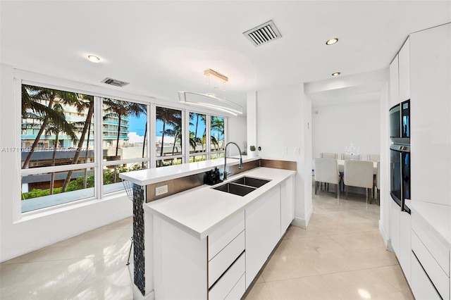 kitchen featuring light tile patterned floors, white cabinetry, oven, and sink