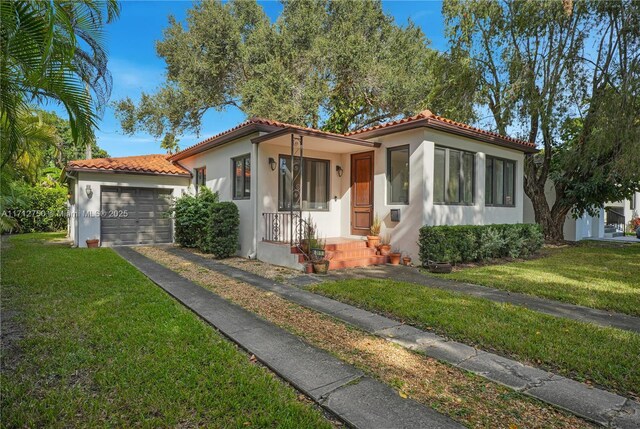 mediterranean / spanish home featuring a garage and a front lawn