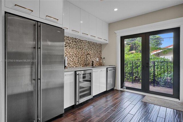 kitchen with sink, white cabinetry, tasteful backsplash, appliances with stainless steel finishes, and beverage cooler