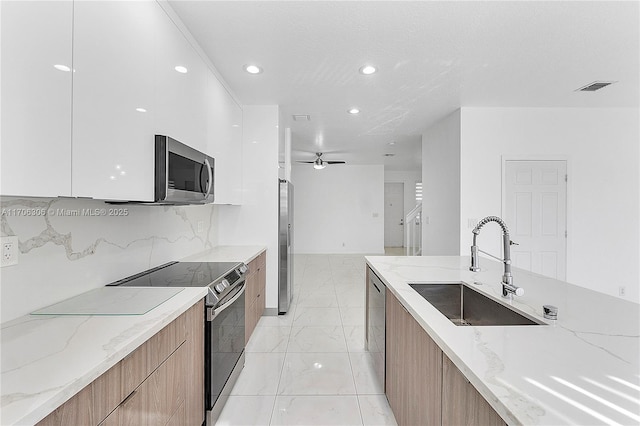 kitchen featuring light stone countertops, sink, white cabinetry, stainless steel appliances, and tasteful backsplash