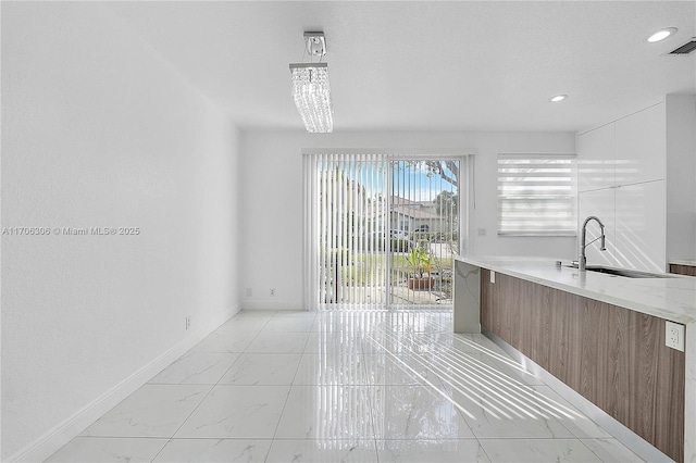 kitchen featuring sink, white cabinets, and a chandelier