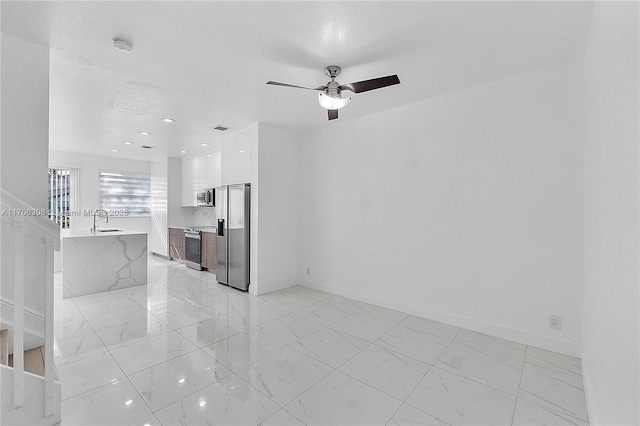 empty room featuring a textured ceiling, ceiling fan, and sink