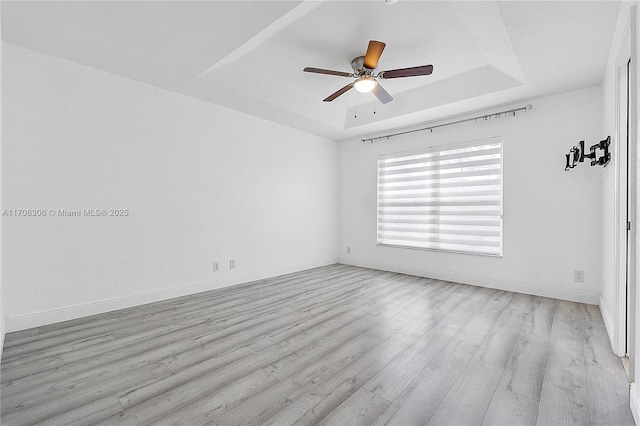 unfurnished room with ceiling fan, light hardwood / wood-style floors, and a raised ceiling