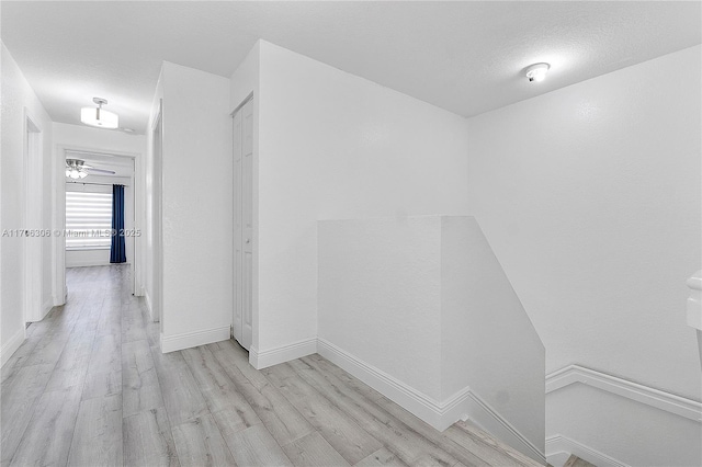 hallway with a textured ceiling and light wood-type flooring