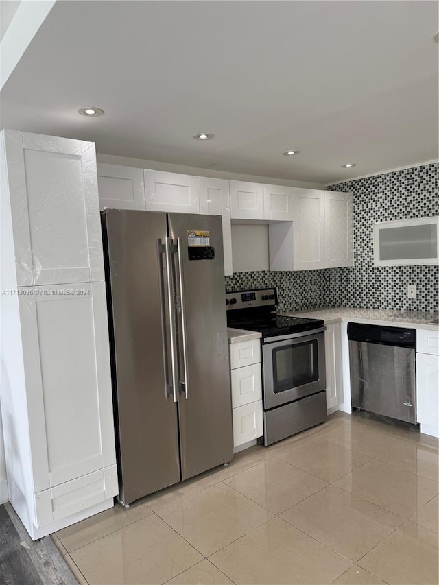 kitchen with decorative backsplash, white cabinets, stainless steel appliances, and light tile patterned floors