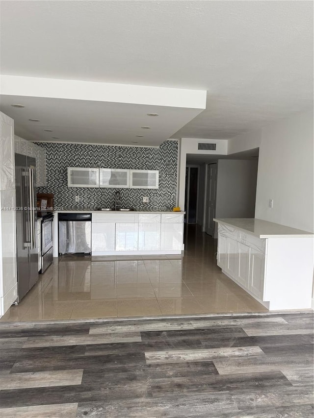 interior space featuring backsplash, dark wood-type flooring, sink, and stainless steel appliances