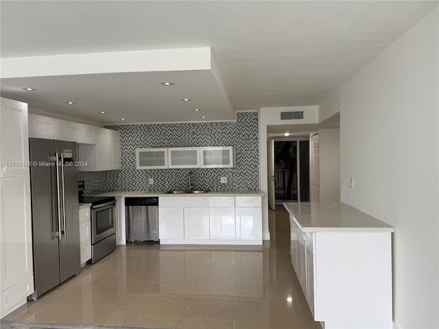 kitchen featuring decorative backsplash, appliances with stainless steel finishes, sink, light tile patterned floors, and white cabinets