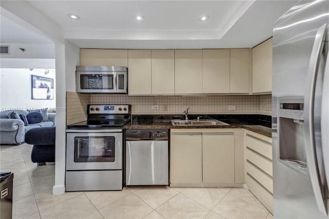 kitchen featuring visible vents, a sink, decorative backsplash, stainless steel appliances, and cream cabinets