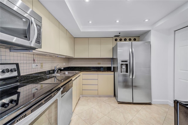 kitchen featuring sink, light tile patterned floors, stainless steel appliances, cream cabinets, and decorative backsplash