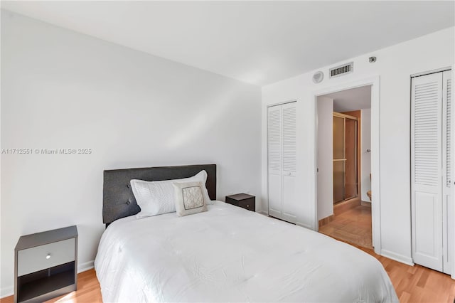 bedroom with multiple closets and light wood-type flooring