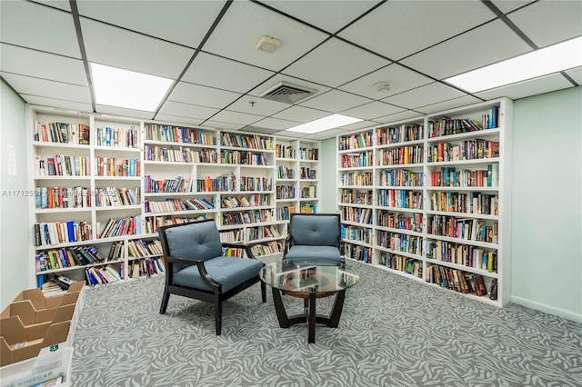 sitting room featuring visible vents, carpet floors, and wall of books