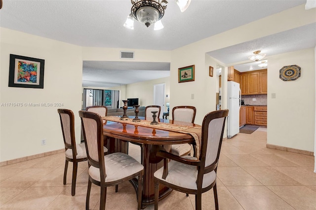 tiled dining space featuring a textured ceiling