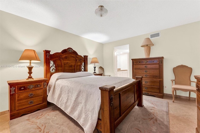 tiled bedroom featuring ensuite bath and a textured ceiling