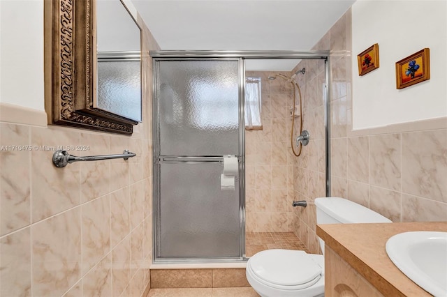 bathroom with an enclosed shower, vanity, toilet, and tile walls