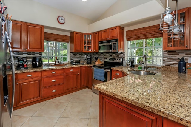 kitchen with vaulted ceiling, pendant lighting, sink, stainless steel appliances, and light stone counters