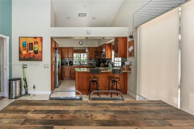 kitchen with pendant lighting, light tile patterned floors, stainless steel refrigerator, a breakfast bar, and kitchen peninsula