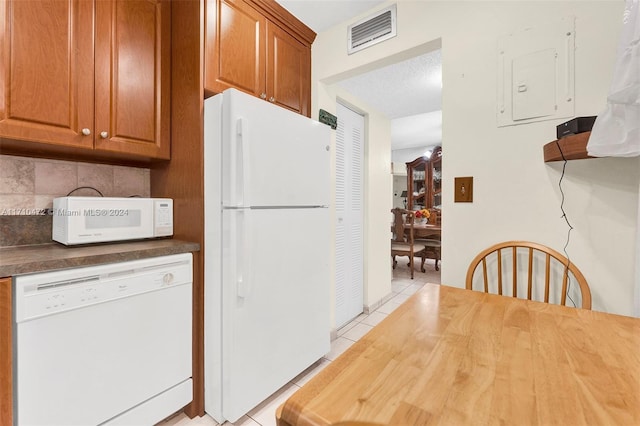 kitchen with electric panel, decorative backsplash, light tile patterned floors, and white appliances