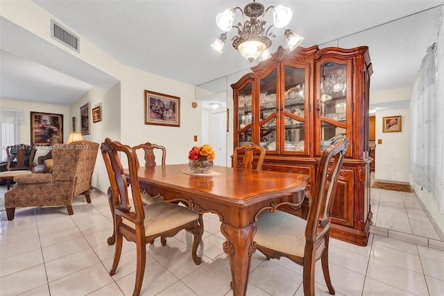 dining space featuring light tile patterned floors, a textured ceiling, and a notable chandelier