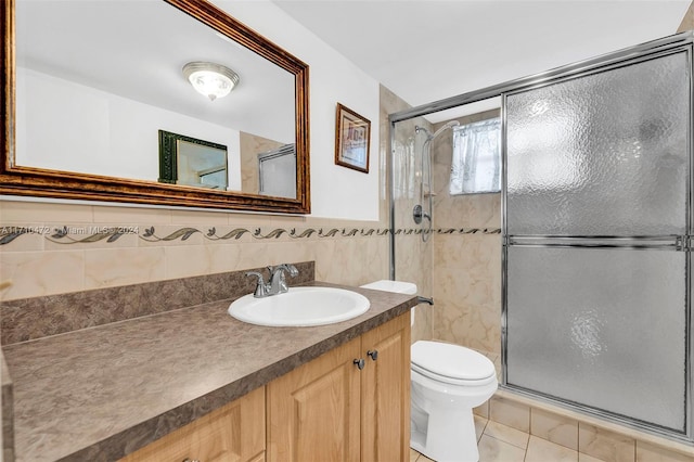 bathroom featuring tile patterned floors, vanity, a shower with door, and tile walls