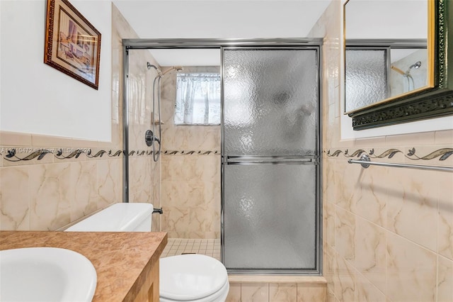 bathroom featuring vanity, toilet, tile walls, and a shower with shower door