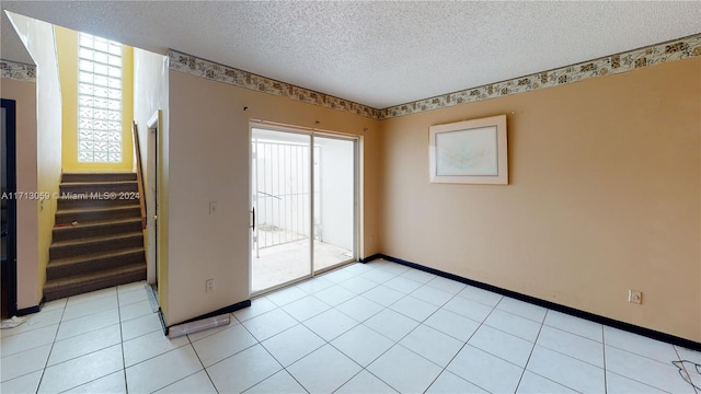 tiled empty room featuring a textured ceiling