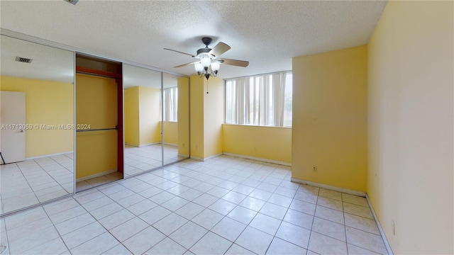 unfurnished bedroom with a textured ceiling, a closet, ceiling fan, and light tile patterned flooring