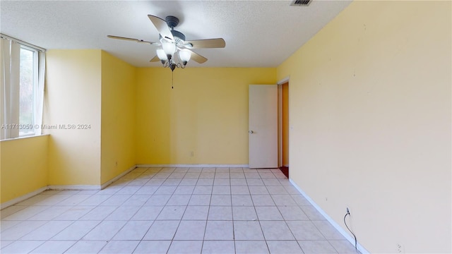 tiled empty room with ceiling fan and a textured ceiling