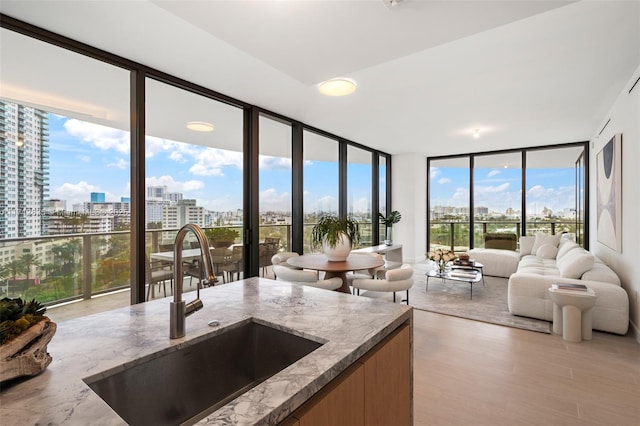 kitchen featuring a view of city, light stone counters, expansive windows, and a sink