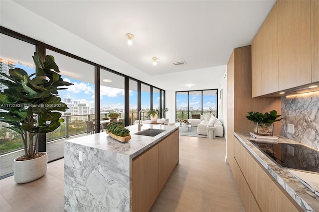 kitchen with light brown cabinets, a sink, visible vents, decorative backsplash, and modern cabinets