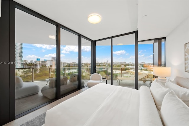 bedroom featuring floor to ceiling windows, a city view, and wood finished floors