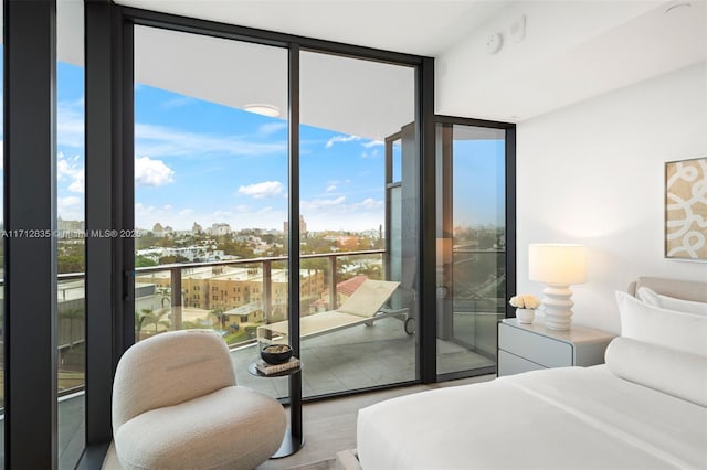 bedroom featuring a city view, a wall of windows, and access to exterior