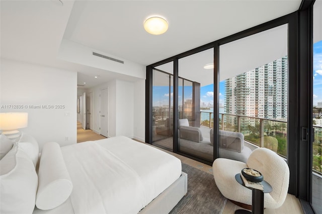 bedroom with expansive windows, access to outside, visible vents, and a city view