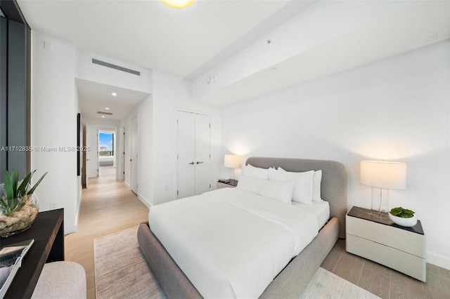 bedroom featuring a closet, visible vents, baseboards, and light wood finished floors