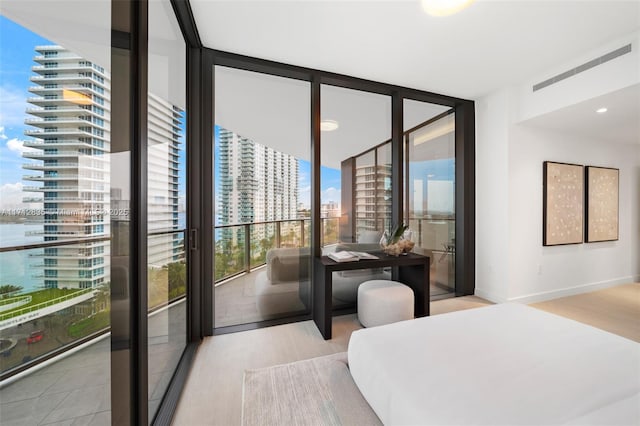 bedroom with a view of city, expansive windows, baseboards, and wood finished floors