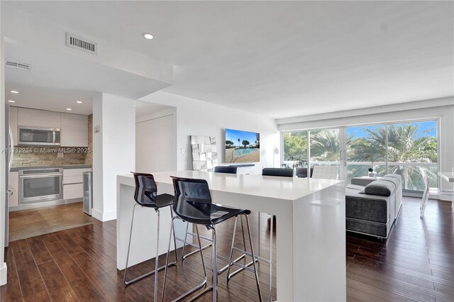 kitchen featuring decorative backsplash, white cabinetry, stainless steel appliances, and dark wood-type flooring