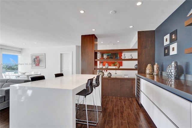 kitchen featuring a breakfast bar, wine cooler, dark hardwood / wood-style floors, and white cabinets