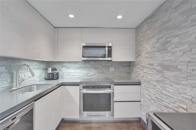 kitchen featuring backsplash, white cabinetry, sink, and appliances with stainless steel finishes