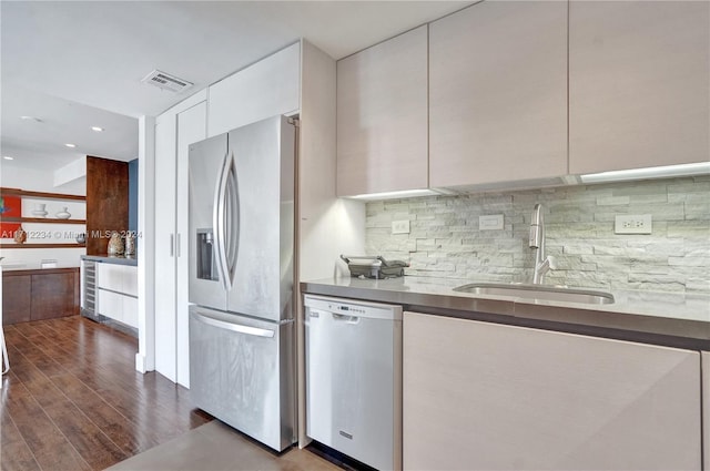 kitchen with backsplash, white cabinets, sink, dark hardwood / wood-style floors, and appliances with stainless steel finishes