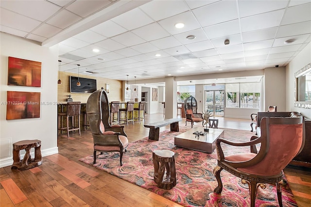 living room with a paneled ceiling, hardwood / wood-style floors, and a healthy amount of sunlight