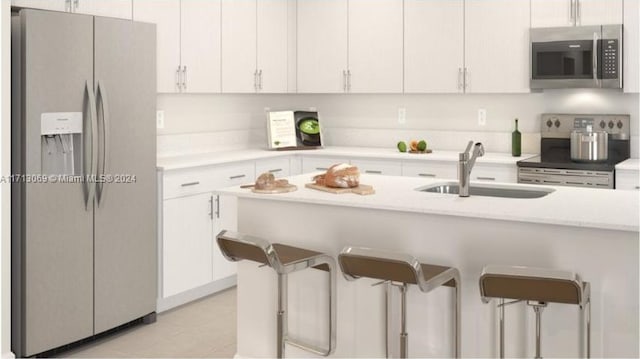 kitchen with a kitchen bar, stainless steel appliances, white cabinetry, and sink