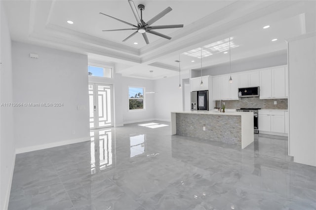 kitchen with white cabinets, a center island with sink, ceiling fan, decorative light fixtures, and stainless steel appliances